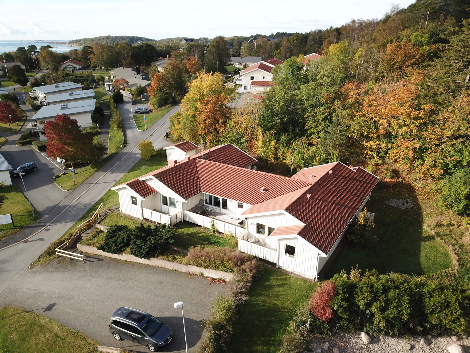 Fjordhems gruppbostad,flygvy över vit byggnad med rött tak vid skog och bostadsområde