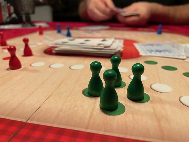 Ett brädspel med gröna och röda spelpjäser på ett bord.