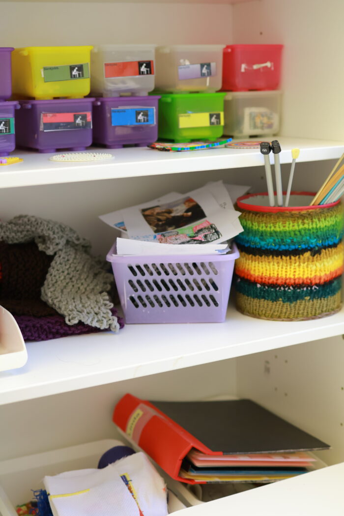 Hyllor med färgglada förvaringslådor, korgar och pysselmaterial som papper och pennor.
