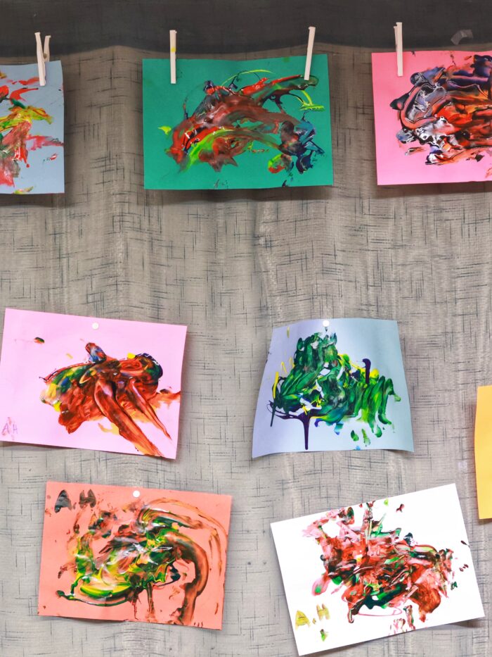 Teckningar i olika färger upphängda på en vägg.