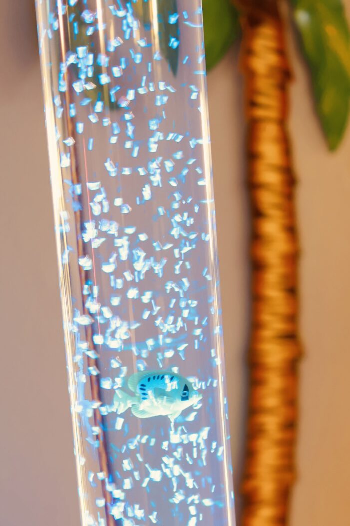 Närbild på ett bubbelrör med ljus och fiskar som flyter runt.