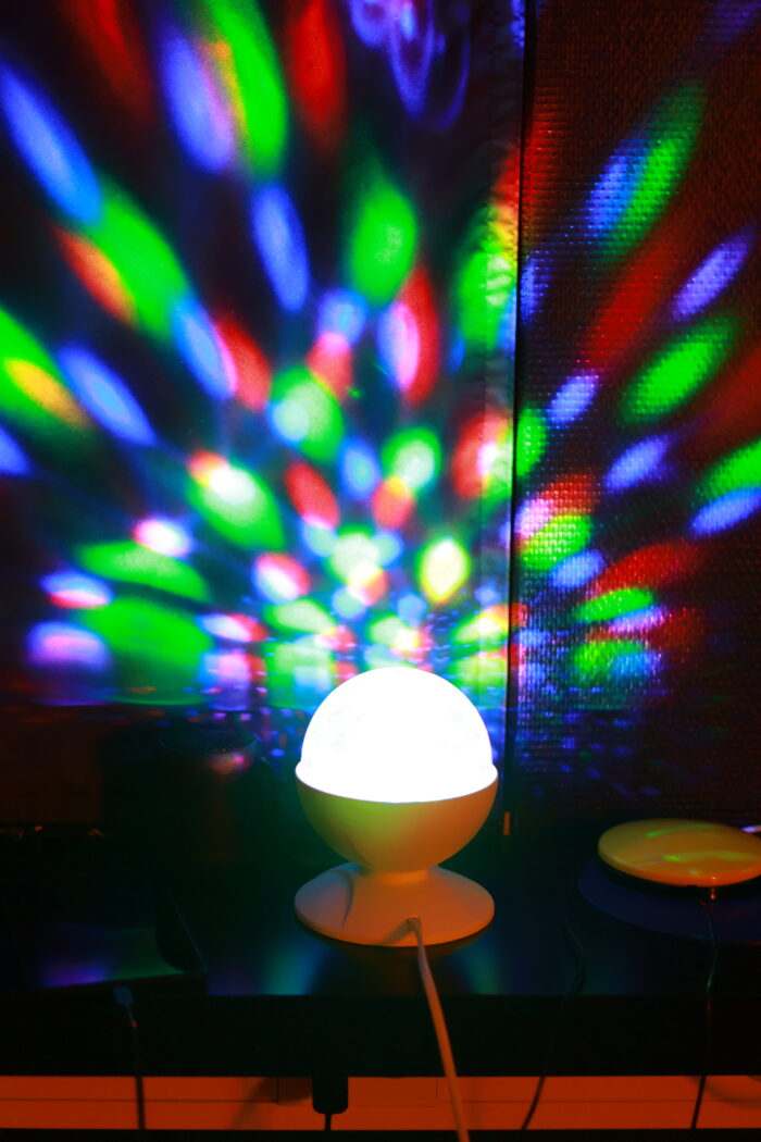 Discolampa som lyser upp färgglatt ljus på väggen bakom.