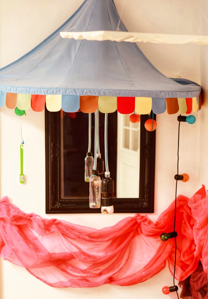 Interiör för sinnesstimulering, med ljusblått tälttak, spegel på väggen, färgglada lampor samt rött böjande tyg som är fäst på väggen.