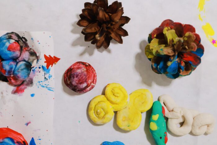 Ett bord med olika pysselföremål,bland annat kottar,färgglada bollar och mjuka former i olika material och färger.