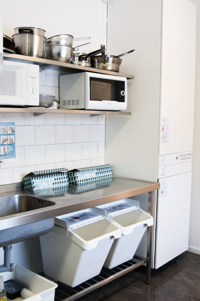 Köksbänk med ett högskåp till höger. Ovanför bänken finns hyllor med micro och kastruller.