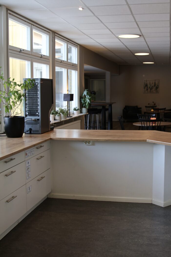 Kafédisk med kaffemaskin ståendes till vänster i bild. I bakgrunden ser man kafébord.