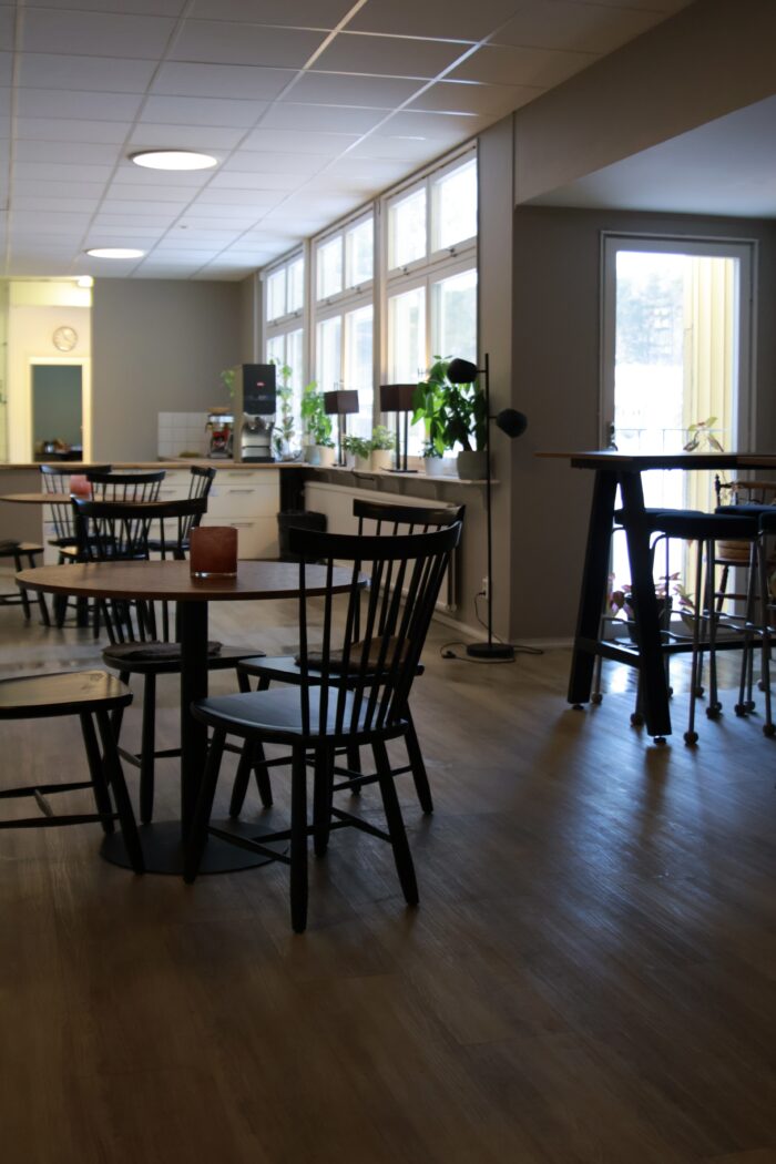 Svarta runda kafébord med svarta stolar. I bakgrunder syns kafédisken.