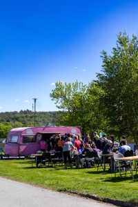 Bild på en rosa foodtruck och en lång kö med människor.